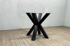 a black table sitting on top of a hard wood floor next to a white wall