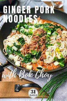 a pan filled with meat and noodles on top of a wooden cutting board