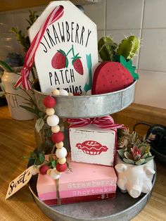 a metal tray filled with assorted items on top of a wooden table next to a potted plant