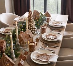 a table set for christmas with gingerbread houses and candles