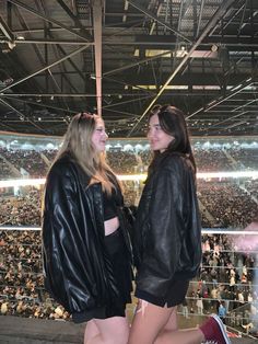 two women standing next to each other in front of an arena full of people at a sporting event