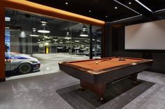 a pool table in front of a projection screen with a car on the wall behind it