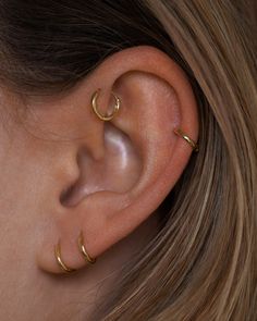 a close up of a person's ear with two small gold hoops on it