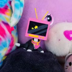 a stuffed animal with a television on it's head sitting next to other stuffed animals