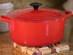 a red casserole with corks on the counter