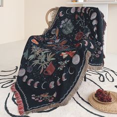 a black blanket sitting on top of a white rug next to a bowl of fruit