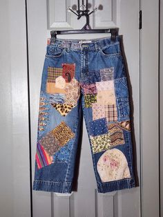 a pair of blue jeans with patches on them hanging from a hanger in front of a door