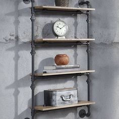 a shelf with some books and a clock on top of it next to a wall