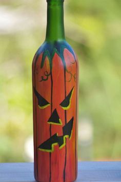 a painted bottle with a jack o lantern face on it sitting on a table outside