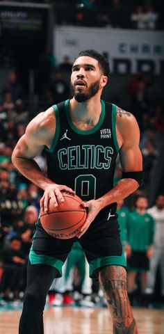 a man holding a basketball in his right hand and wearing a green jersey with the number 10 on it