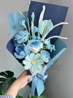 a bouquet of flowers is being held up by someone's hand in front of a plant