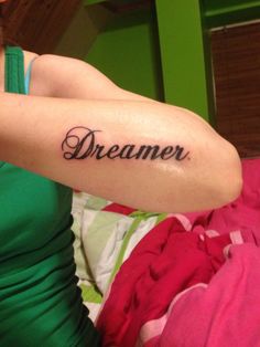 a woman with a tattoo on her arm that reads,'dreamer'in cursive font