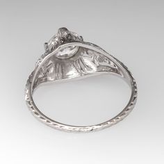 Circa 1930s ring features a domed pierced design and accented with engraved wheat details. The ring is centered with one (1) old European cut diamond set into four-prong head. The ring measures 8.8mm at the top, rises 6.2mm above the finger, tapering to 1.2mm wide and 0.8mm thick at the base of the shank. Vintage Rose Cut Round Diamond Ring, Vintage Engraved Ring With Diamond Round Cut, Vintage Engraved Diamond Ring With Single-cut Diamonds, Vintage Diamond White Round Cut Ring, Antique Platinum Filigree Ring With Oval Shape, Vintage Filigree Ring With Single Cut Diamonds, Vintage Brilliant Cut Round Band Rings, Vintage Engraved Ring With Single Cut Diamonds, Vintage White Gold Filigree Ring