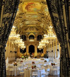 an ornately decorated ballroom with chandeliers and white linens on the tables