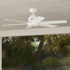 a white ceiling fan mounted to the side of a wooden roof over an outdoor living area