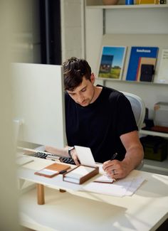 a man sitting at a desk writing on a piece of paper with a calculator in front of him