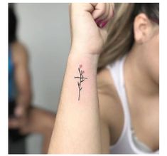 a woman with a small cross tattoo on her left arm, and another person in the background