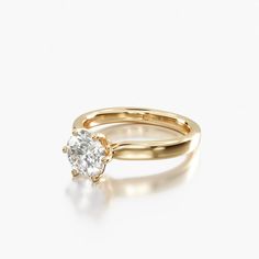 a yellow gold engagement ring with a single diamond in the center, on a white background