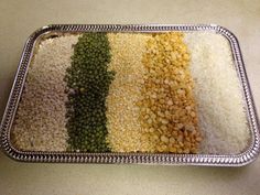 a tray filled with different types of beans and rice on top of a white counter