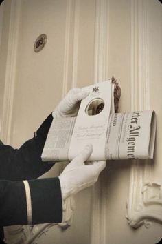 a person in white gloves holding up a book