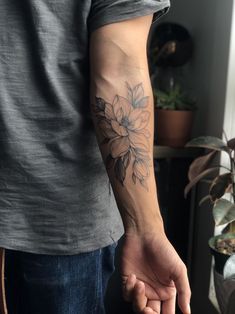 a man with a flower tattoo on his arm holding the hand of another person's hand