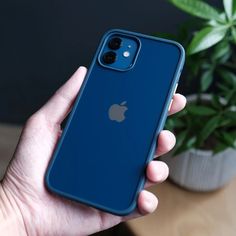 a person holding an iphone 11 in their left hand, next to a potted plant