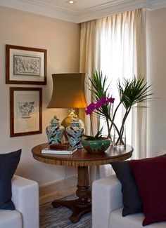 two vases with flowers sit on a table in front of a lamp and couch