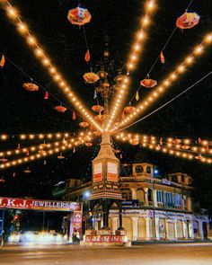 the lights are hanging over the street in front of an old fashioned building at night