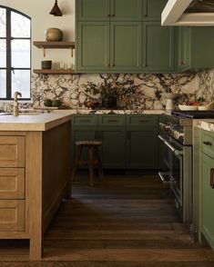 a kitchen with green cabinets and marble counter tops