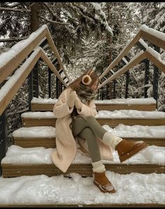 a woman sitting on steps in the snow with her feet up and wearing warm clothing