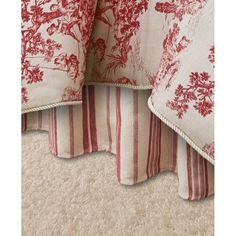 red and white bedding with floral print on the bottom, along with striped pillows