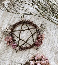 an arrangement of dried flowers and branches on a lace tablecloth with a wicker star