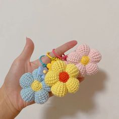 small crocheted flowers are being held in someone's hand with the fingers