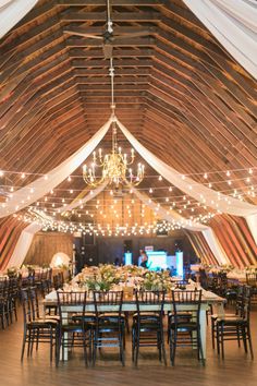 the inside of a barn with tables and chairs set up for a formal dinner party