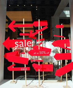 several red signs are in front of a store window that says sale all at 50 % off