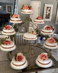 a table topped with lots of white cakes covered in frosting and pink flower decorations