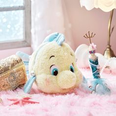 a stuffed animal sitting on top of a pink rug next to a lamp and other items