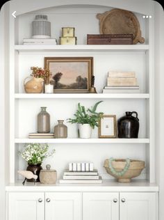 a white bookcase filled with books and vases