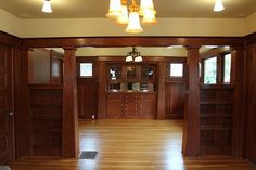 an empty living room with wood paneling and chandelier