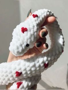 someone is holding up a knitted toy with hearts on it's arms and fingers