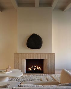 a living room with a fire place in the center and a large rock on the wall