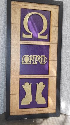 a wooden frame with metal letters and symbols on the front in purple, gold and black