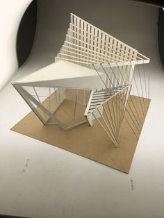 a model of a building made out of wood and white paper on top of a brown mat