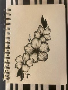 a black and white drawing of flowers on a piece of paper next to a pen