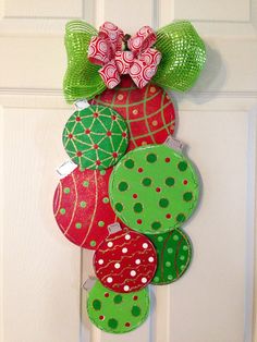 a door hanger decorated with christmas ornaments and bows on it's front door