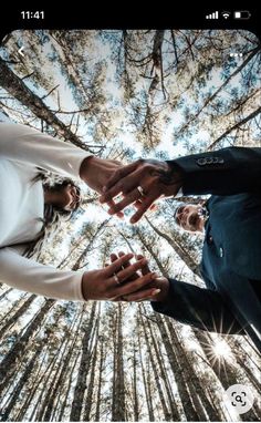 two people holding hands in the middle of a forest