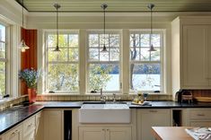 a kitchen with white cabinets, black counter tops and an island in front of two windows