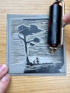 a person is holding a bottle opener near a paper cutout with a tree on it