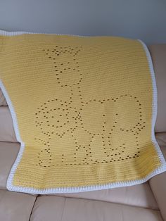 a yellow crocheted blanket sitting on top of a couch next to a pillow