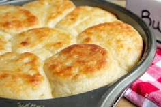 a pan filled with biscuits sitting on top of a table next to a red and white checkered towel